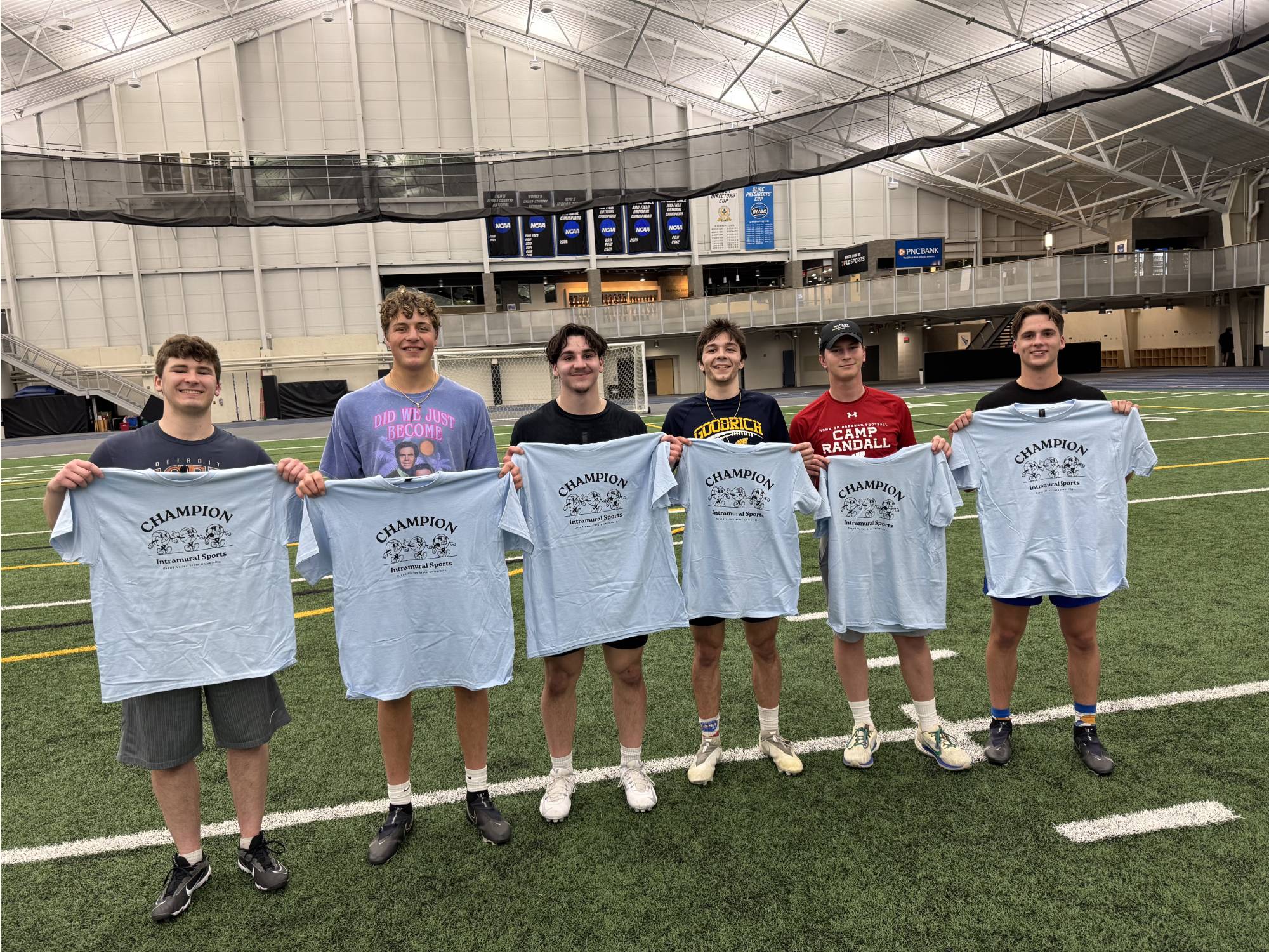 Grand valley students posing with championship t-shirt for winning the 4v4 indoor flag football bracket.